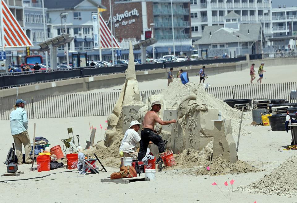 Sculptors Abe Waterman, Bruce Phillips and Matthew Deibert work on creating the sponsorship site for the 23rd Hampton Beach Sand Sculpting Classic June 12, 2023.