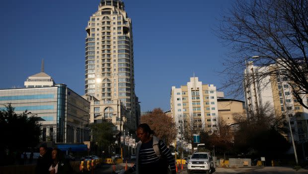 Michelangelo towers are seen as pedestrians make their way to work past road construction site in Sandton, South Africa.