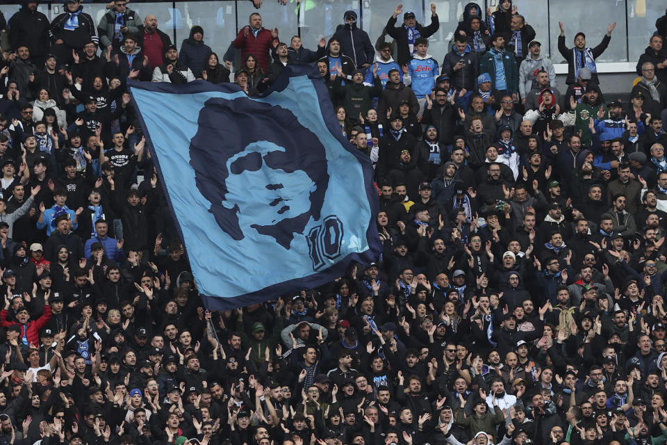 Hinchas del Napoli despliegan pancartas de Diego Maradona durante el partido contra Hellas Verona en la Serie A, el 15 de abril de 2023. El club está a punto de consagrarse campeón de la liga italiana por primera vez después de 30 años, desde la era de Diego Maradona. (AP Foto/Alessandro Garofalo/LaPresse vía AP)