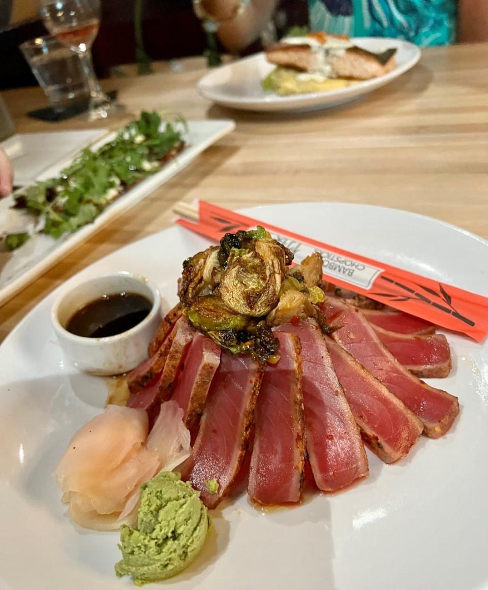 The seared sashimi yellowfina tuna and coconut sticky rice entrée is joined by thai-chili brussels sprouts and ponzu sauce.