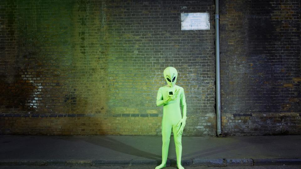 man dressed in alien costume looking at mobile