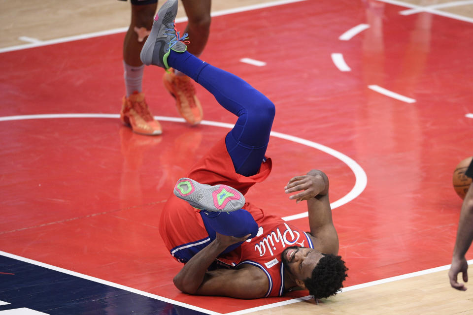 Philadelphia 76ers center Joel Embiid (21) grabs his knee after he was injured during the second half of the team's NBA basketball game against the Washington Wizards, Friday, March 12, 2021, in Washington. (AP Photo/Nick Wass)