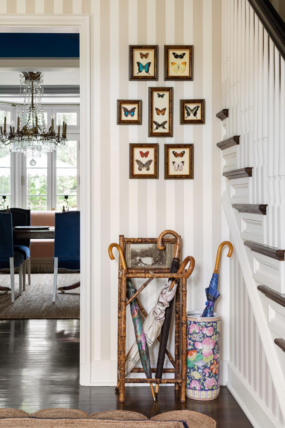 Entryway with striped wallpaper and lots of umbrellas in a stand.