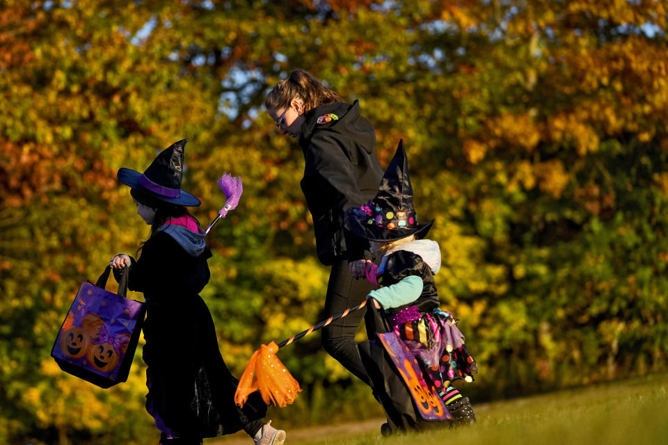 Parents and children leave after receiving free Halloween candy from a local businessman, Tuesday, Oct. 31, 2023, in Lewiston, Maine. Locals seek a return to normalcy after a shooting that claimed 18 lives in their community on Oct. 25. (AP Photo/Matt York)