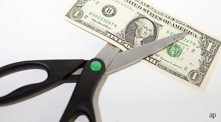 Scissors cutting a dollar note