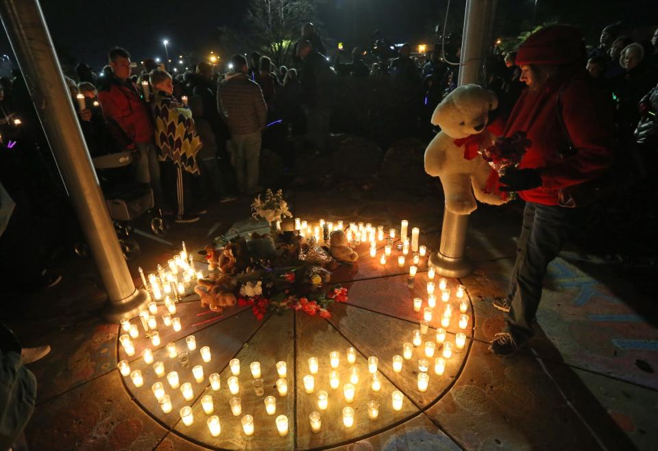 Barb Moran places a stuffed animal in the center of a memorial in honor of Kate Kasten, her children, Zoe Kasten, 8, and Jonathan Kasten, 10, and Kate Kasten's mother, Jane Moeckel, 61, at Harris Elementary School in St. Charles, Mo., Sunday, Dec. 30, 2018. Prosecutors say a St. Louis-area man charged with fatally shooting his girlfriend, her two young children and her mother could face the death penalty once the investigation is complete. (Laurie Skrivan/St. Louis Post-Dispatch via AP)