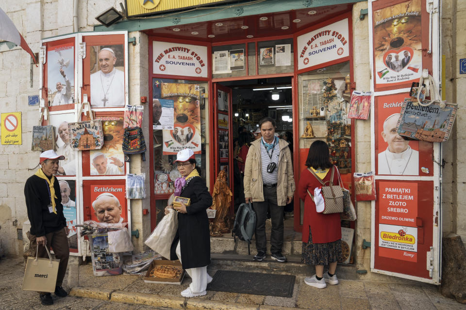 Tourists visit a gift shop in Manger Square, outside the Church of the Nativity, traditionally believed by Christians to be the birthplace of Jesus Christ, ahead of Christmas, in the West Bank city of Bethlehem, Saturday, Dec. 3, 2022. Business in Bethlehem is looking up this Christmas as the traditional birthplace of Jesus recovers from a two-year downturn during the coronavirus pandemic. Streets are already bustling with visitors, stores and hotels are fully booked and a recent jump in Israeli-Palestinian fighting appears to be having little effect on the vital tourism industry. (AP Photo/ Mahmoud Illean)