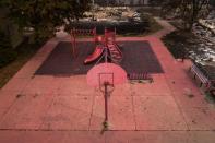 Red fire retardant blankets basketball post and a playground in the aftermath of the Almeda fire in Talent, Oregon