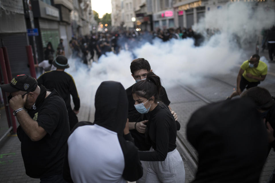 Protesters react to tear gas fired by French riot police during a march against police brutality and racism in Marseille, France, Saturday, June 13, 2020, organized by supporters of Adama Traore, who died in police custody in 2016 in circumstances that remain unclear despite four years of back-and-forth autopsies. Several demonstrations went ahead Saturday inspired by the Black Lives Matter movement in the U.S. (AP Photo/Daniel Cole)