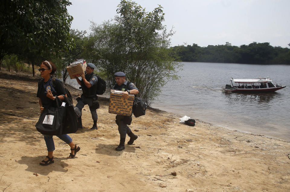 An electoral worker and military police officers unload electronic voting machines to be taken to a polling station a day ahead of the country's general elections, at the Bela Vista do Jaraqui community in Manaus, Amazonas state, Brazil, Saturday, Oct. 1, 2022. (AP Photo/Edmar Barros)