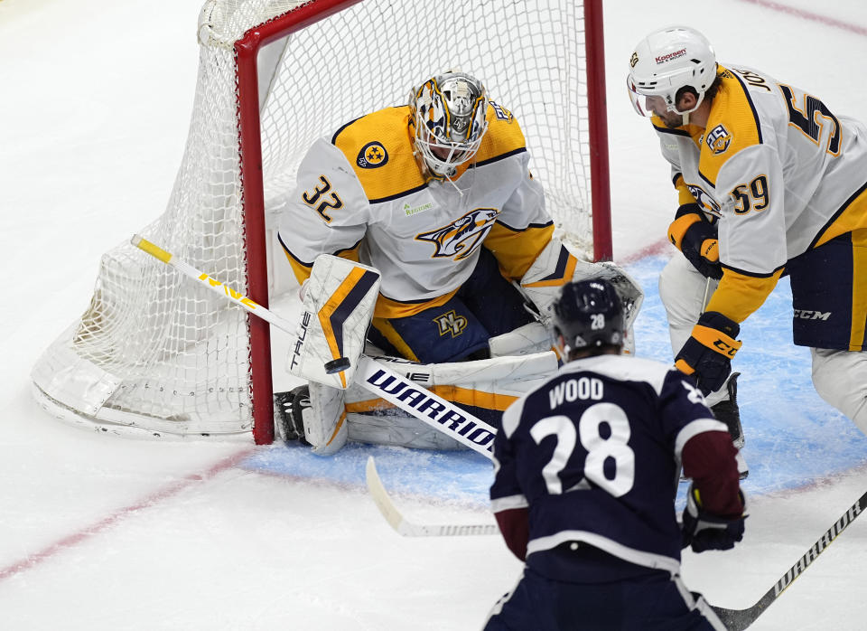 Nashville Predators goaltender Kevin Lankinen (32) makes a glove save of a shot from Colorado Avalanche left wing Miles Wood (28) as Nashville defenseman Roman Josi (59) looks on in the first period of an NHL hockey game Saturday, March 30, 2024, in Denver. (AP Photo/David Zalubowski)