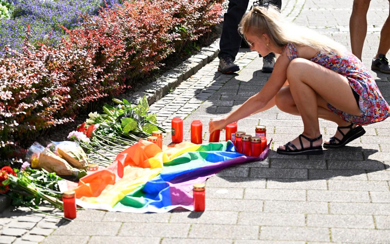 A young woman lights a candle at a makeshift memorial to the victims