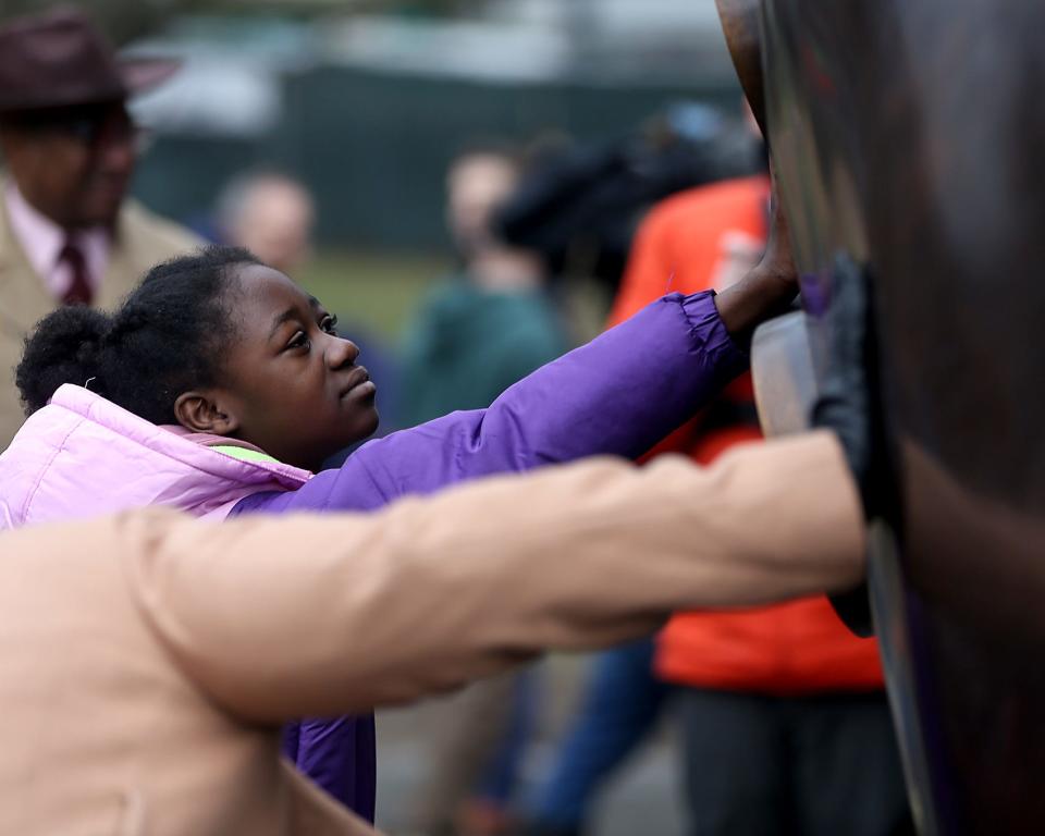 Shyairah Smith Clark O'Neal, 11, of Brookline, touches "The Embrace" after its unveiling Friday on Boston Common. Clark O'Neal and her stepfather attend the 12th Baptist Church in Boston, the same church that the Rev. Martin Luther King Jr. and Coretta Scott King attended when they lived in the city decades ago.