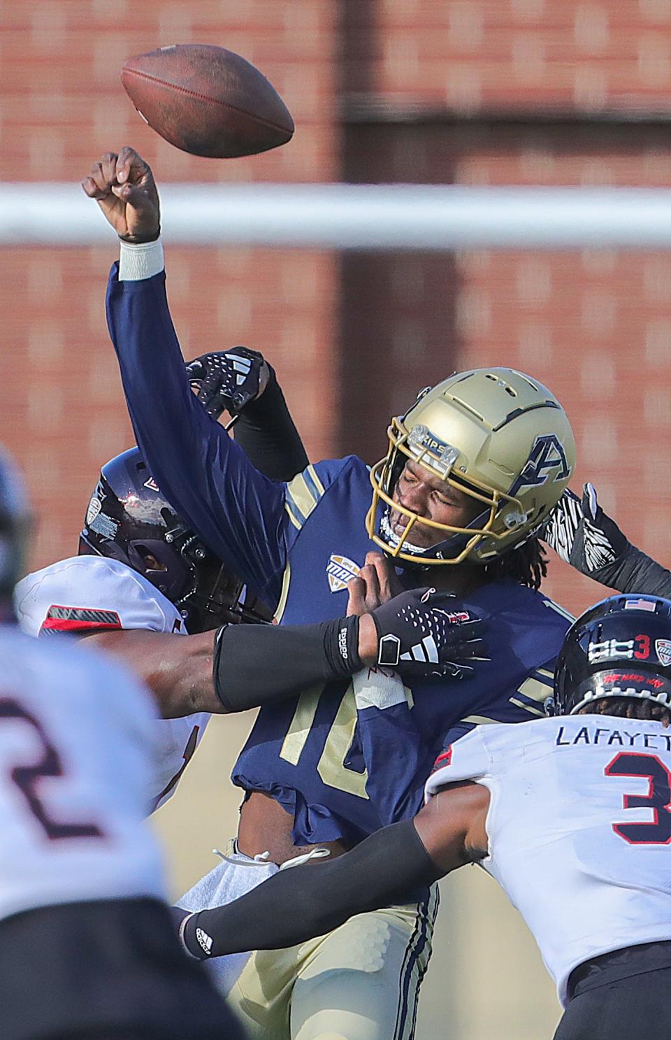 University of Akron quarterback Tahj Bullock is hit by NIU defensive tackle Devonte O'Malley during the second quarter on Saturday in Akron.