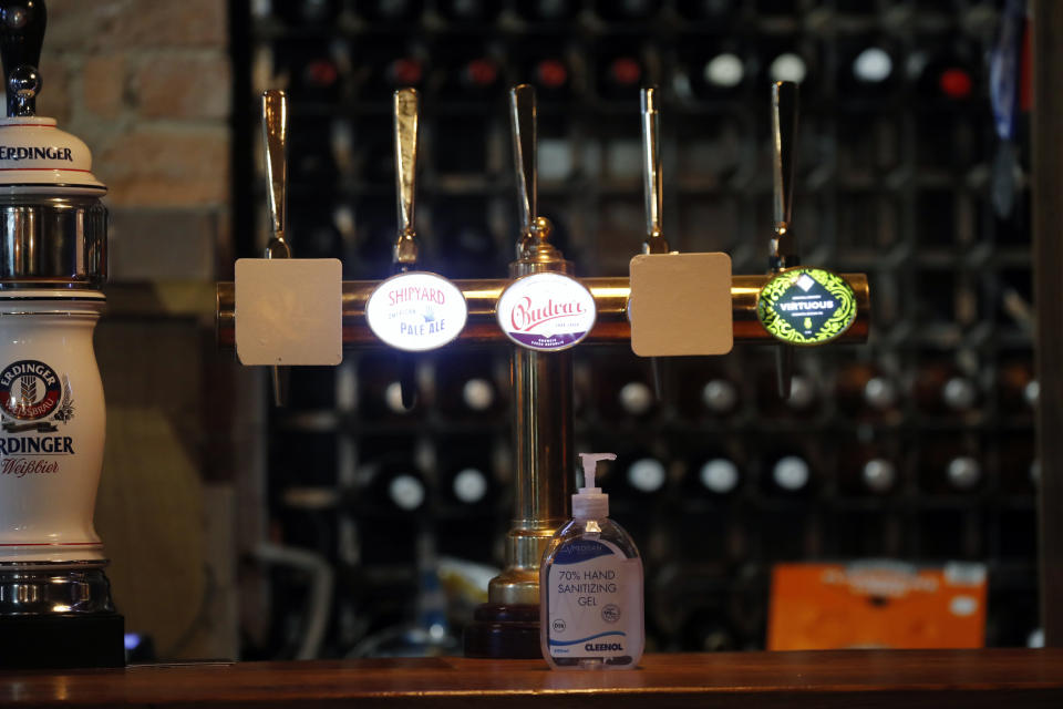 Hand sanitizer is left on a bar in a pub as new measures across the region are set to come into force in Liverpool, England, Wednesday, Oct. 14, 2020. New plans unveiled this week show Liverpool is in the highest-risk category, and its pubs, gyms and betting shops have been shut.(AP Photo/Frank Augstein)