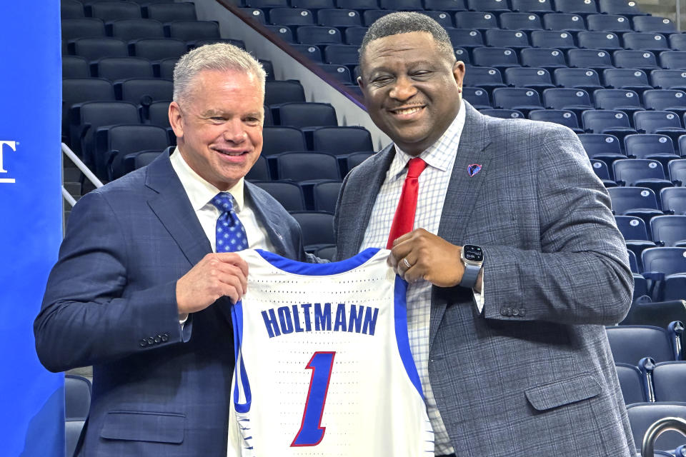 DePaul men's basketball new NCAA college basketball head coach Chris Holtmann, left, and DePaul vice president and director of athletics Dewayne Peevy hold Holtmann's jersey as they pose for photos at a news conference in Chicago, Monday, March 18, 2024. (AP Photo/Andrew Seligman)