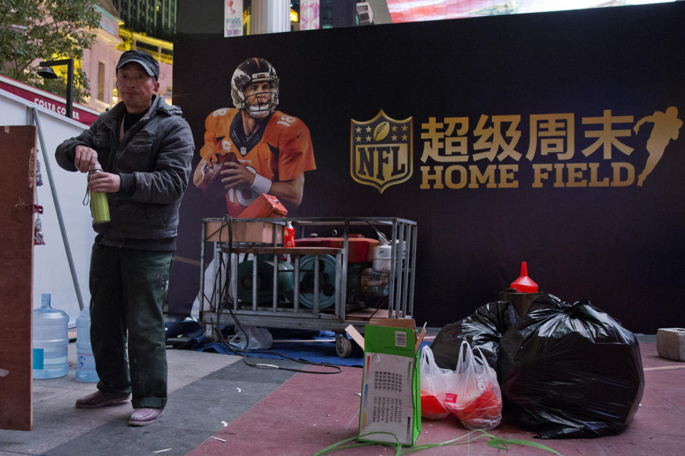 A worker turns the cap of his thermos near a billboard promoting a National Football League event in Beijing, China, Thursday, Oct. 22, 2015. The NFL has been aggressively promoting football in China hoping to take advantage of rising income and growing taste for exotic foreign sports. (AP Photo/Ng Han Guan)