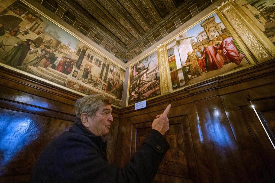 Piergiorgo Millich, gran guardián de la Escuela Dálmata mira pinturas del artista renacentista Vittore Carpaccio en la planta baja de la Escuela Dálmata en Venecia, Italia,el el 7 de diciembre de 2022. De izquierda a derecha "San Trifón y el basilisco", una réplica de "La agonía en el jardín" que esta´siendo restaurada por Valentina Piovan y "Cristo ascendido". Una exposición de las pinturas de Carpaccio llegará a Venecia en marzo tras su paso por la Galería Nacional de Washington donde se presentará hasta el 12 de febrero de 2023. (AP Photo Domenico Stinellis)