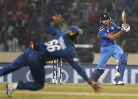 Virat Kohli plays a ball as Sri Lanka's Lahiru Thirimanne (L) jumps to catch during their ICC Twenty20 World Cup cricket final match at the Sher-E-Bangla National Cricket Stadium in Dhaka April 6, 2014. REUTERS/Andrew Biraj