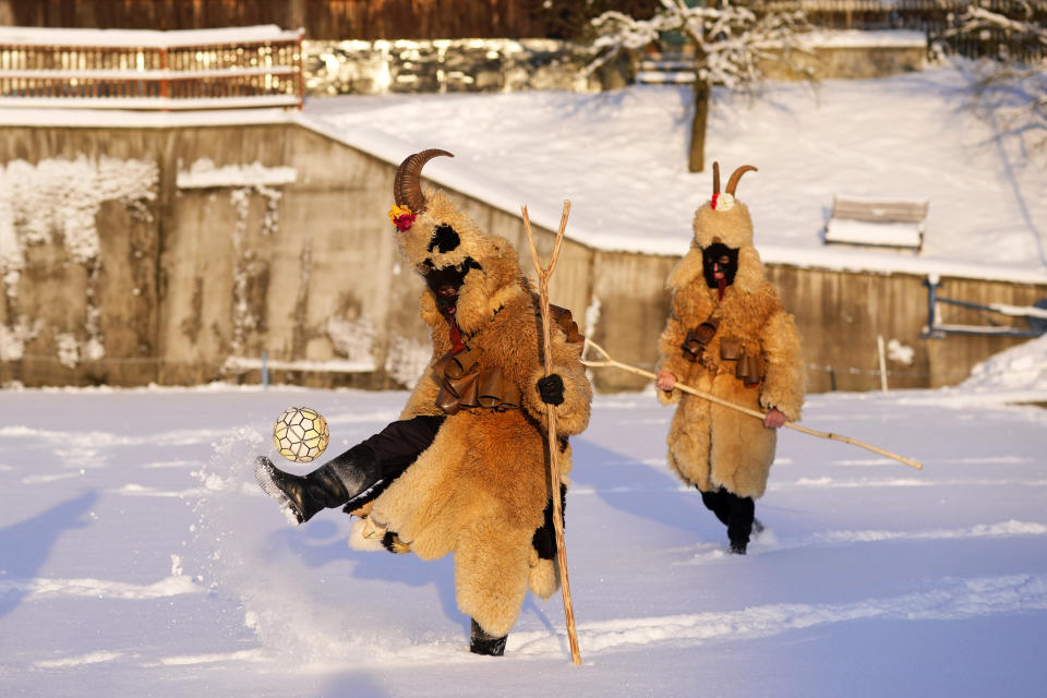 Revelers depicting devils play with a ball before a traditional St. Nicholas procession in the village of Lidecko, Czech Republic, Monday, Dec. 4, 2023. This pre-Christmas tradition has survived for centuries in a few villages in the eastern part of the country. The whole group parades through village for the weekend, going from door to door. St. Nicholas presents the kids with sweets. The devils wearing home made masks of sheep skin and the white creatures representing death with scythes frighten them. (AP Photo/Petr David Josek)