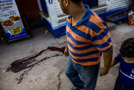 <p>Father and son pass by a pool of blood left by the body of a 20 year<br>old boy killed few hours before in Tegucigalpa, Honduras. (Photo: Francesca Volpi) </p>