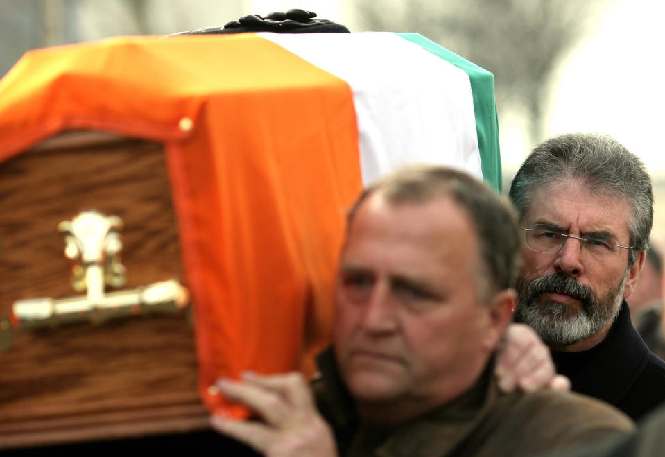 ARCHIVO - En esta imagen del martes 19 de febrero de 2008 el presidente de Sinn Fein, Gerry Adams (derecha) ayuda a cargar el ataúd del jefe militar del IRA Brendan Hughes en Belfast, Iralanda del Norte. (Foto AP/Peter Morrison, Archivo)