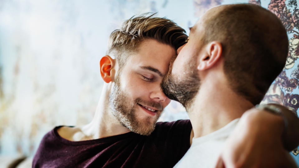 A man kisses another man's forehead