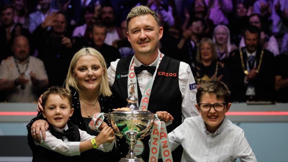 Kyren Wilson celebrates with his family in front of the World Championship trophy