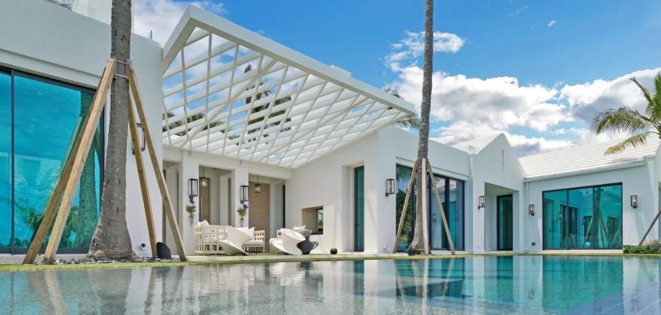The front doors at 149 E. Inlet Drive in Palm Beach open onto a pergola-covered breezeway facing the pool.