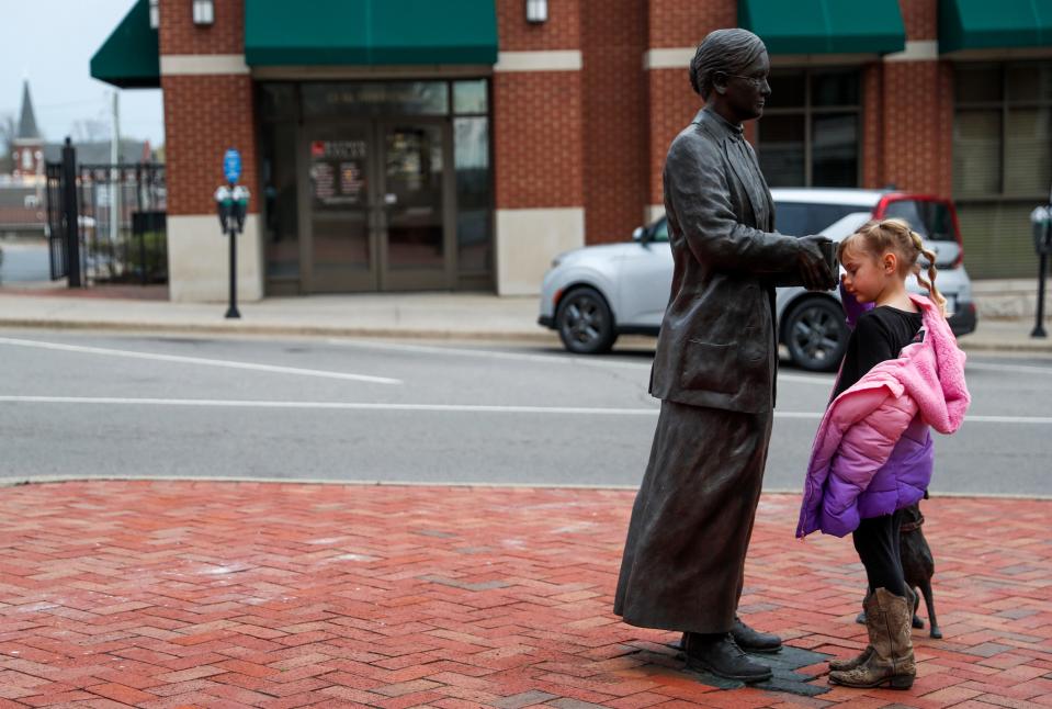 Kathryn Holloran, 6, Billy and Teresa McCraw's granddaughter, peers through the opening of an old camera held by the statue of Lenora Witzel at the Historic Montgomery County Courthouse in Clarksville, Tenn., on Monday, April 4, 2022. Holloran lives and works on the farm, having written a letter for the commission about the expansion and asking how people would pick strawberries and disappointed that she wouldn't be washing buckets for people anymore.