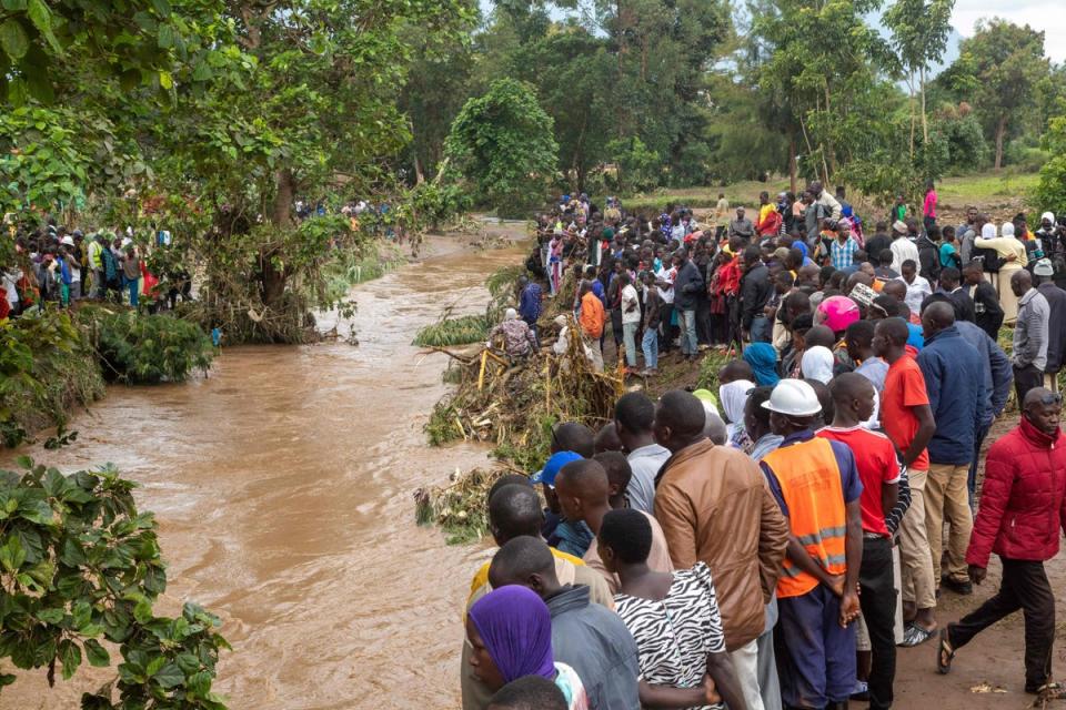 Onlookers watch as people search for flood victims at the Nabuyonga River in Uganda on Tuesday (AFP via Getty Images)