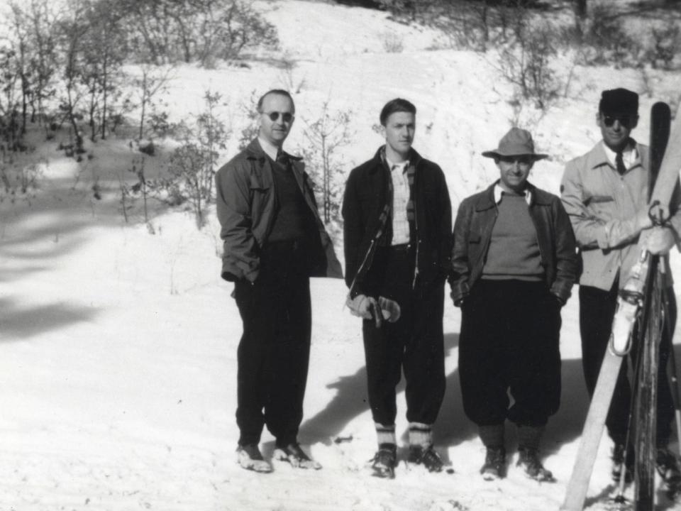 Four men, including Enrico Fermi, stand on snow with one holding skis near Los Alamos, New Mexico, in the mid-1940s
