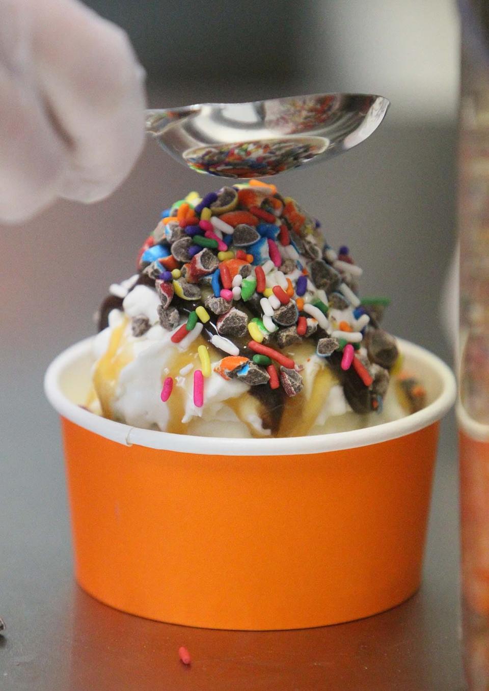 Travis Monty-Bromer, the owner of Penguin Ice Cream in Copley, makes a Create-Your-Own-Sundae made with cookies and cream ice cream, whipped cream, chocolate and caramel syrups, chocolate chunks and sprinkles.