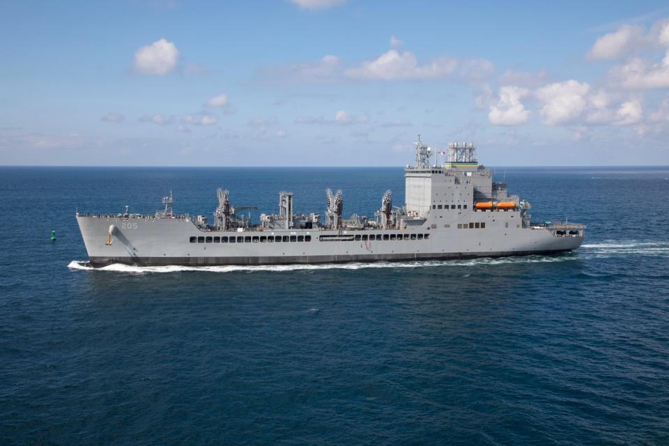 USNS John Lewis (T-AO-205) on the ocean against a sunny sky.