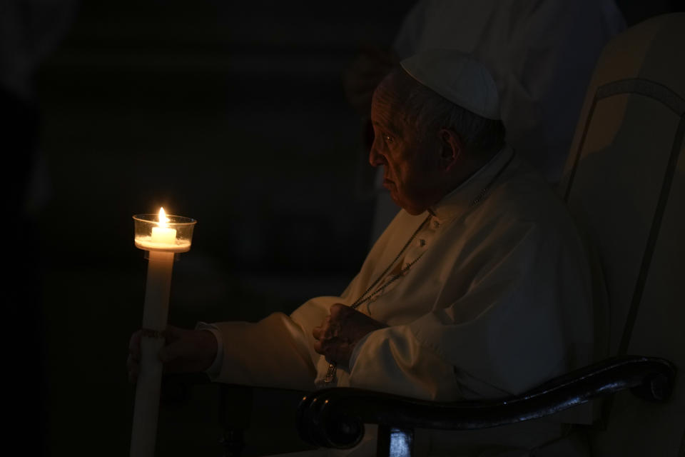Pope Francis holds a Paschal candle as he presides over a Easter vigil ceremony in a darkened St. Peter's Basilica at the Vatican, Saturday, April 16, 2022. (AP Photo/Alessandra Tarantino)