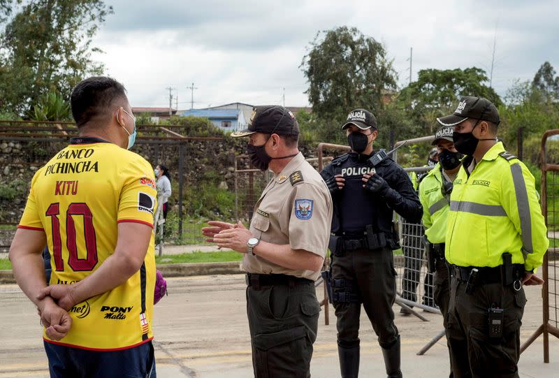 Familiares hablan con la policía afuera de las oficinas del Instituto de Medicina Forense y Ciencias Forenses luego de que los cuerpos de varios reclusos, que murieron luego de que estallara un motín en una prisión local, fueron llevados en Cuenca, Ecuador