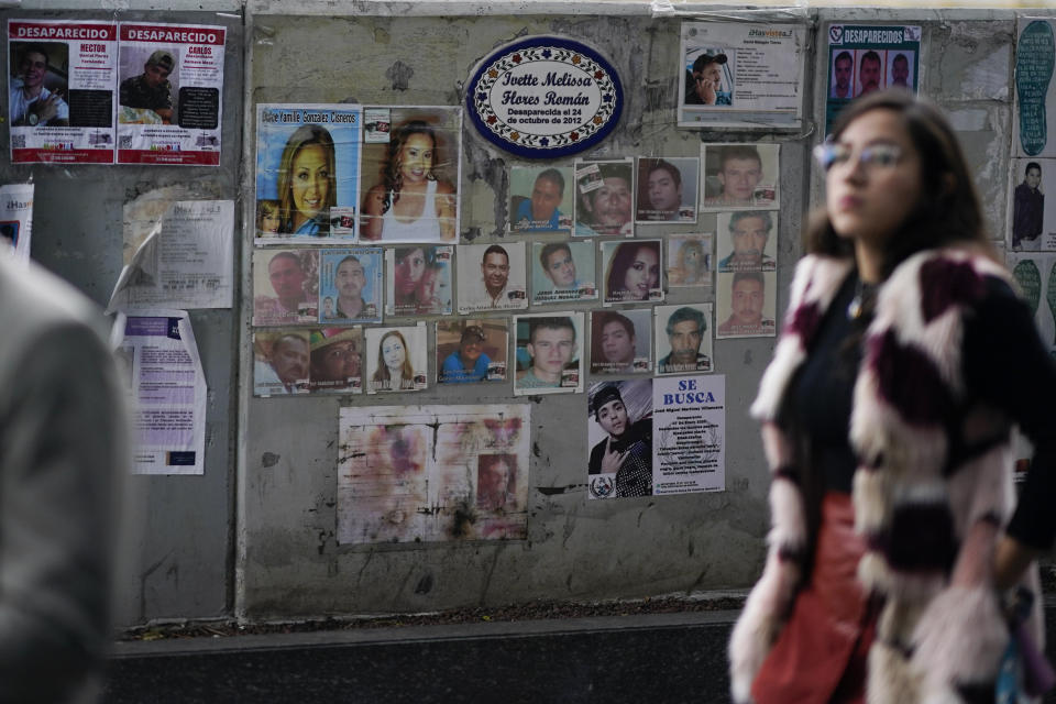 A woman passes in front of photographs of missing persons in front of the Attorney General's office in Mexico City, Wednesday, Dec. 6, 2023. Families of Mexico’s estimated 113,000 ‘disappeared’ are outraged after finding out that the administration of President Andres Manuel Lopez has spent almost a year, lots of money and thousands of hours of work combing databases to see if a supposedly ‘missing’ person has applied for a loan, paid taxes, registered to vote or gotten a flu shot. (AP Photo/Eduardo Verdugo)