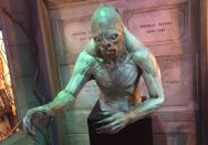 <p>This freaky prop appears in one of Bruce Wayne’s visions. Behind the creature are the tombs of Bruce’s parents, Martha and Thomas, and grandparents Laura and Patrick. </p>