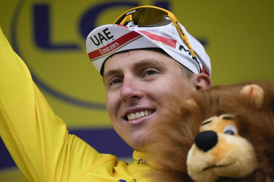 Slovenia's Tadej Pogacar, wearing the overall leader's yellow jersey, celebrates on the podium after the eighth stage of the Tour de France cycling race over 150.8 kilometers (93.7 miles) with start in Oyonnax and finish in Le Grand-Bornand, France,Saturday, July 3, 2021. (AP Photo/Christophe Ena)