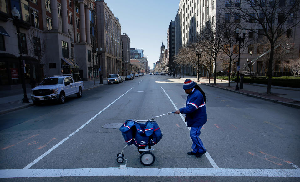 BOSTON, MA - MARCH 18: A USPS letter carrier crosses a quiet Boylston Street with greatly reduced foot and vehicle traffic in Boston on March 18, 2020. Fewer people are out and about as they try to prevent the spread of coronavirus. (Photo by Lane Turner/The Boston Globe via Getty Images)