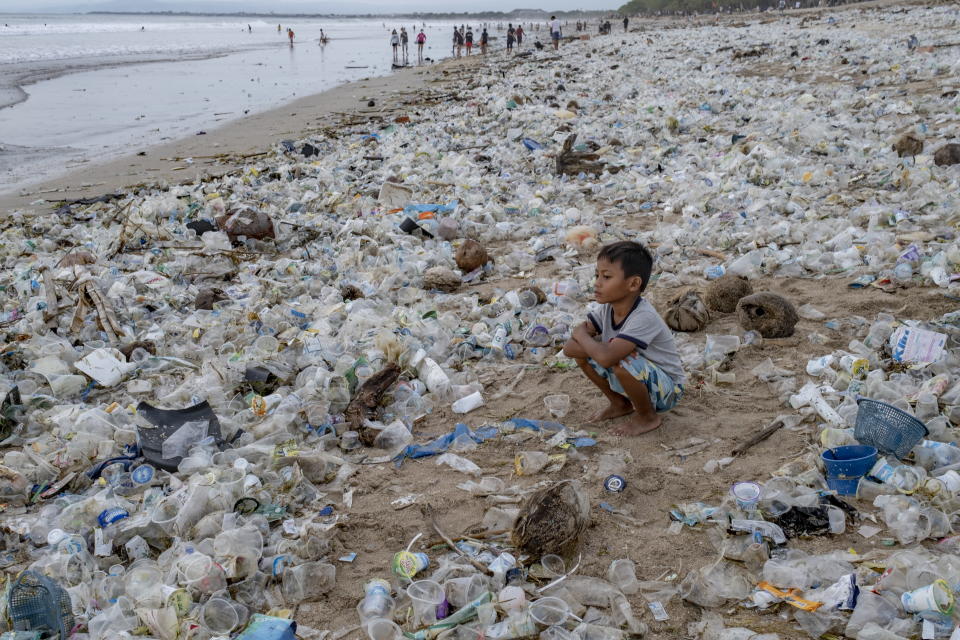 A child squats among the rubbish on an Indonesian beach.