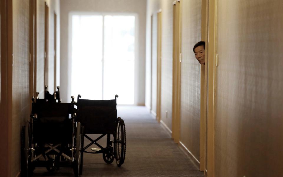 An elderly South Korean man waits in a hotel room