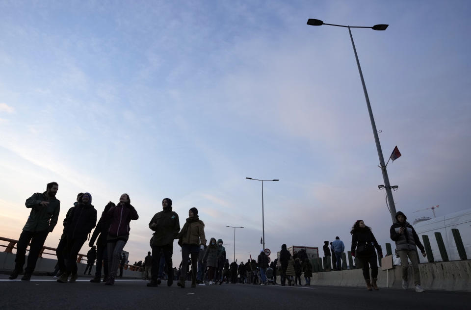 Protesters walk on the highway, during a protest in Belgrade, Serbia, Saturday, Dec. 4, 2021. Thousands of protesters have gathered in Belgrade and other Serbian towns and villages to block roads and bridges despite police warnings and an intimidation campaign launched by authorities against the participants. (AP Photo/Darko Vojinovic)