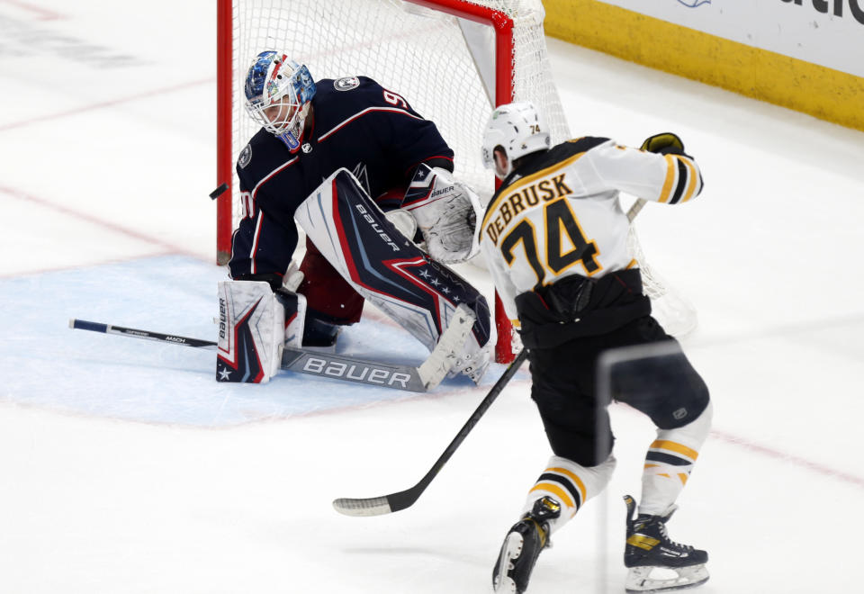 Boston Bruins forward Jake DeBrusk, right scores the winning goal past Columbus Blue Jackets goalie Elvis Merzlikins in an overtime period of an NHL hockey game in Columbus, Ohio, Monday, April 4, 2022. (AP Photo/Paul Vernon)