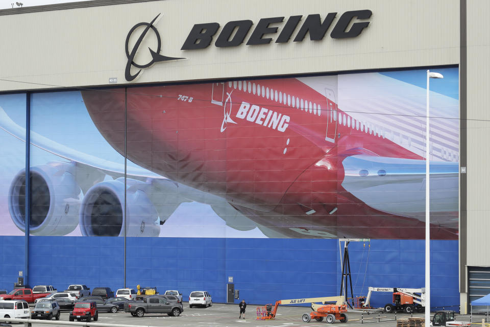 A worker walks near a mural of a Boeing 747-8 airplane at the company's manufacturing facility in Everett, Wash., Monday, March 23, 2020, north of Seattle. Boeing announced Monday that it will be suspending operations and production at its Seattle area facilities due to the spread of the new coronavirus. (AP Photo/Ted S. Warren)