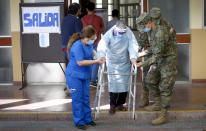 An elderly man is assisted by military police and a woman after voting during a referendum to decide whether the country should replace its 40-year-old constitution, in Santiago, Chile, Sunday, Oct. 25, 2020. (AP Photo/Luis Hidalgo)