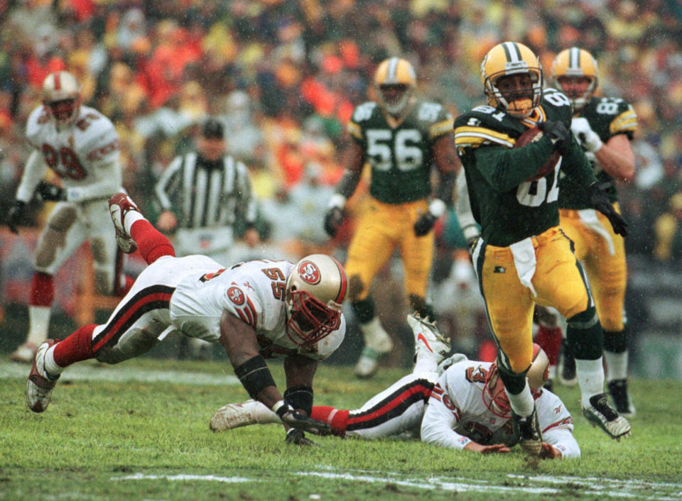 FILE - In this Jan. 4, 1997, file photo, Green Bay Packers' Desmond Howard eludes San Francisco 49ers Kevin Mitchell (55) and punter Tommy Thompson on the way to a touchdown on a punt return in the first half of an NL football game in Green Bay, Wisc. The two teams that have combined for nine Super Bowl titles will meet with a spot in the ultimate game on the line once again when the 49ers (14-3) host the Packers (14-3) in the NFC championship game on Sunday, Jan. 19, 2020.(AP Photo/David Boe, File)