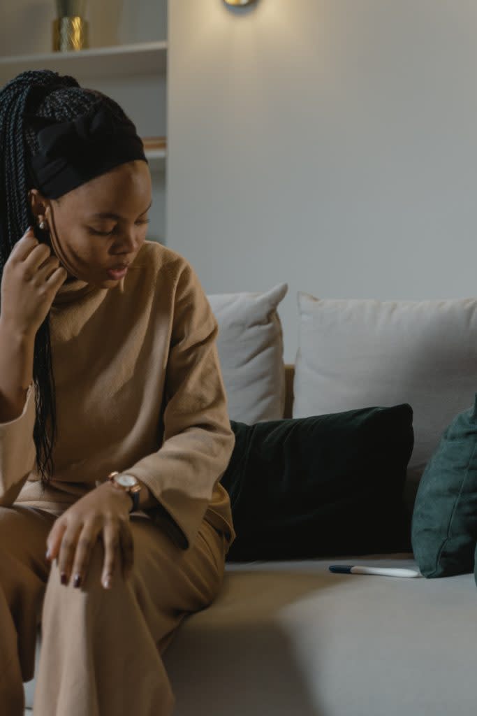 Black woman looking at a pregnancy test while sitting on the couch