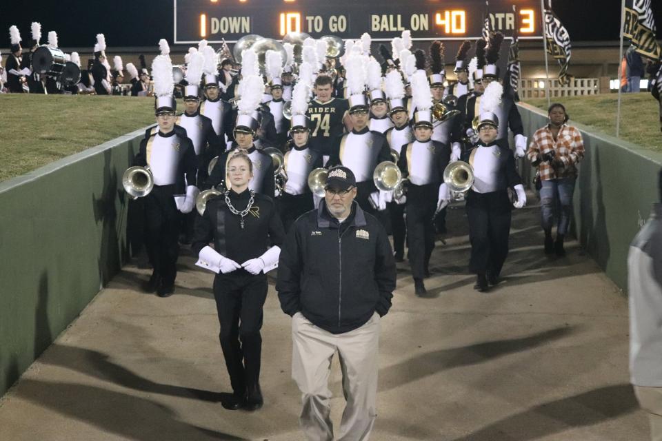 Rider band director Loy Studer leads his students onto the field before a football game at Memorial Stadium.