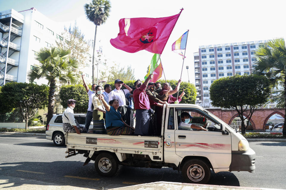Supporters and monks wave Buddhist religious and military flags onboard a vehicle Tuesday, Feb. 2, 2021, in Yangon, Myanmar. Hundreds of members of Myanmar's Parliament remained confined inside their government housing in the country's capital on Tuesday, a day after the military staged a coup and detained senior politicians including Nobel laureate and de facto leader Aung San Suu Kyi. (AP Photo/Thein Zaw)